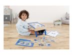 Child playing with a magnetic drawing board, puzzle, and learning clock on a wooden floor.