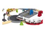 Toy train set with a station, a yellow train, and a white train on tracks.