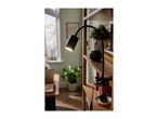 Black clip-on lamp illuminating a wooden bookshelf with plants and decor.