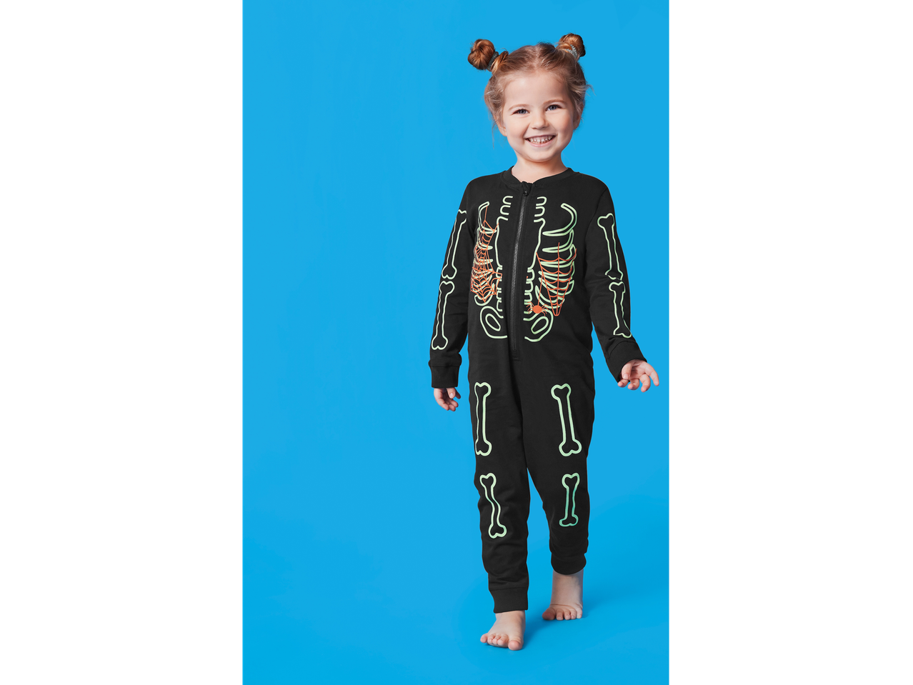 Lupilu® Pijama: Fetiță în pijama neagră cu schelet, zâmbind.