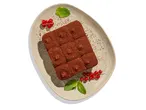 Csokoládés sütemény mentalevéllel és piros ribizlivel díszítve.