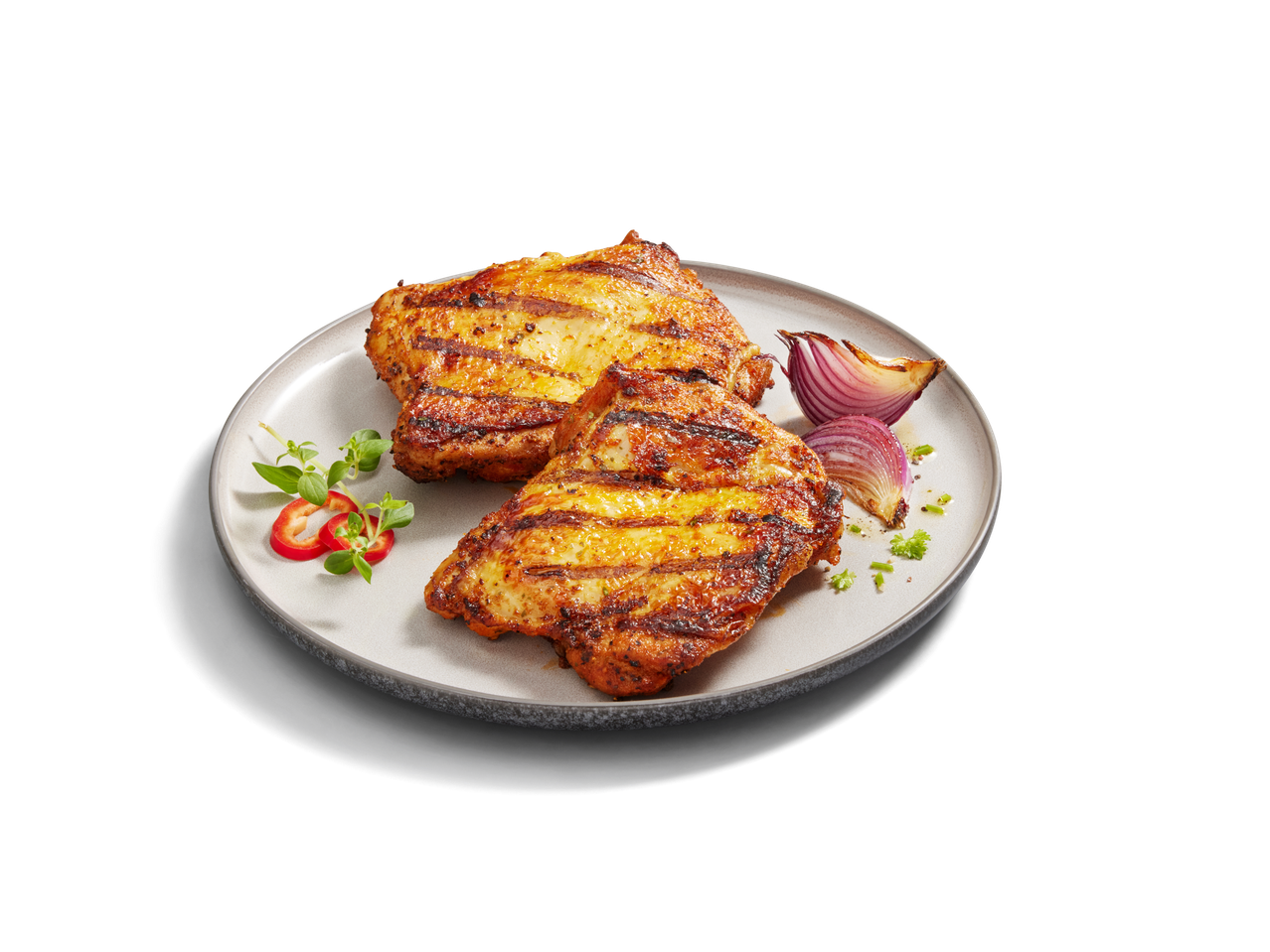 Zwei gegrillte Hähnchenbrustfilets mit roter Zwiebel und Kräutern auf einem Teller.