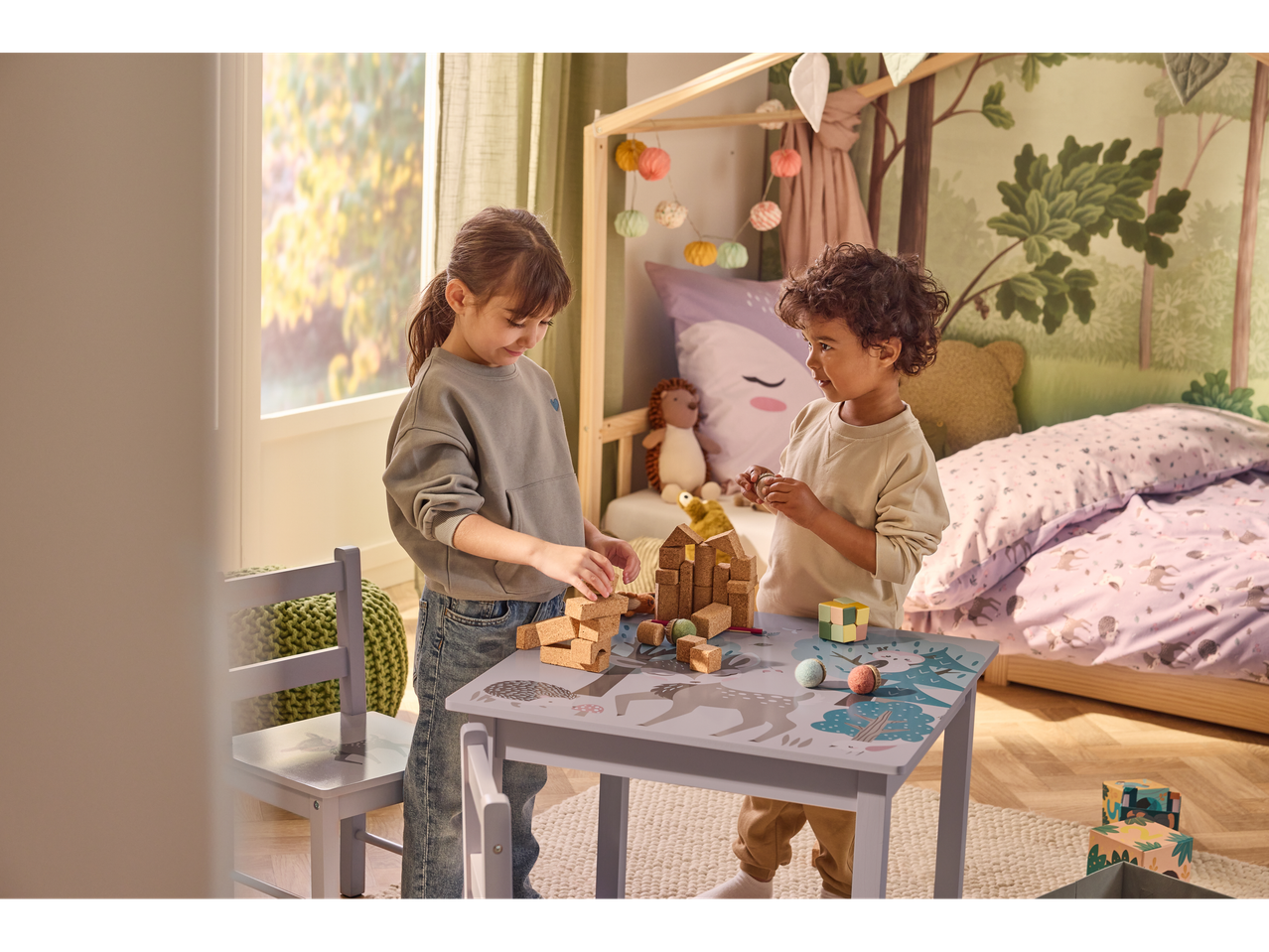 Kaks last mängivad ehitusklotsidega metsaloomade motiividega laua taga lastetoas.