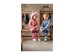 Two laughing children in colorful rain suits and rubber boots sitting on a bench.