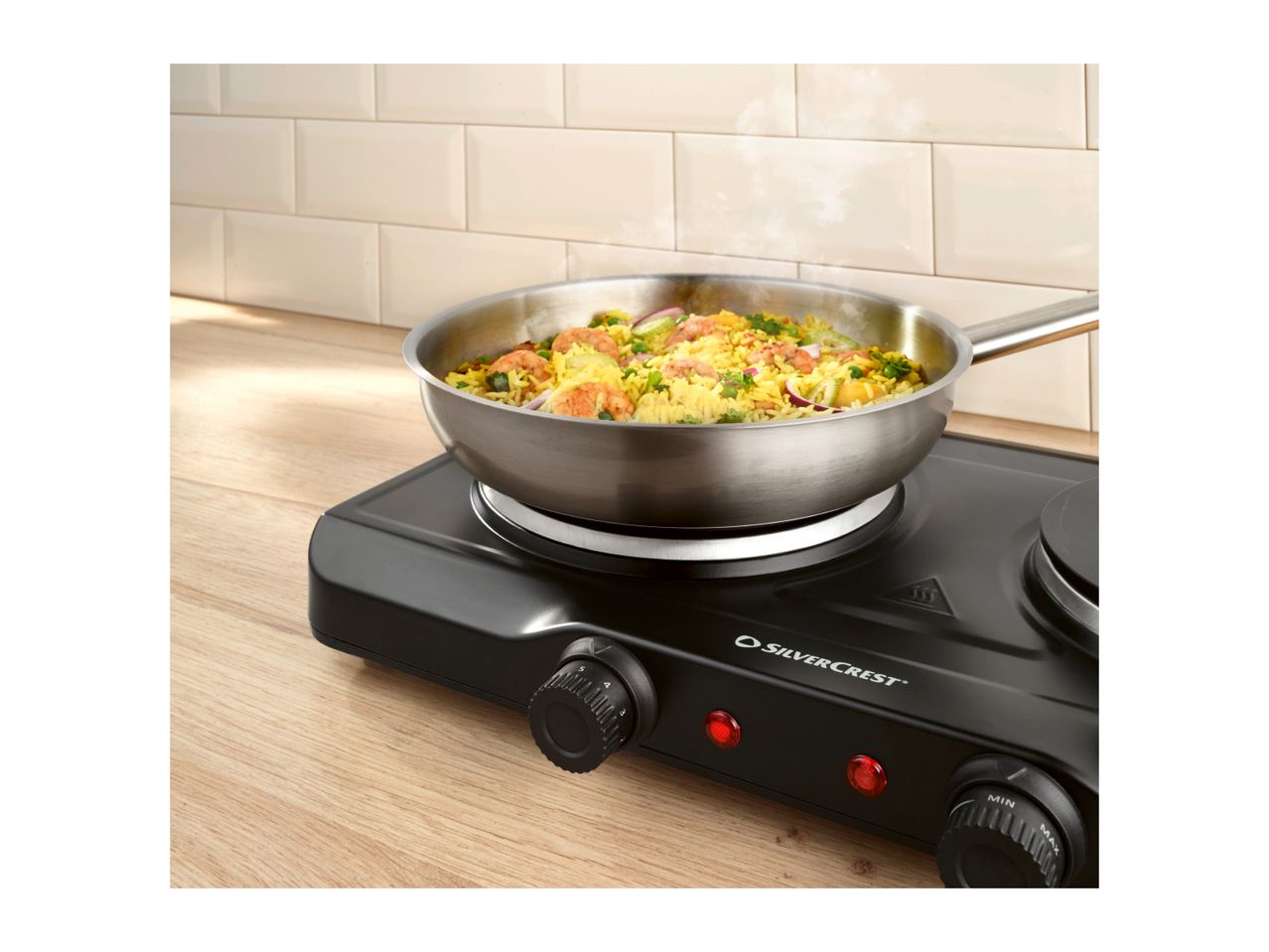 Portable electric hob with a pan of rice and shrimp, on a wooden countertop.