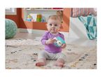 A baby in a purple top and patterned pants sits on a rug, holding a hedgehog-shaped teether.
