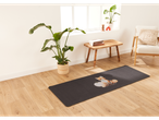 A dark gray mat with a fox and pumpkins on a light wood floor in a living room.