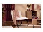 A cozy living room with a white boucle chair, pink throw, and wooden furniture.
