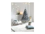 Flocked Christmas tree in a white room with a faux fur rug and festive decorations.