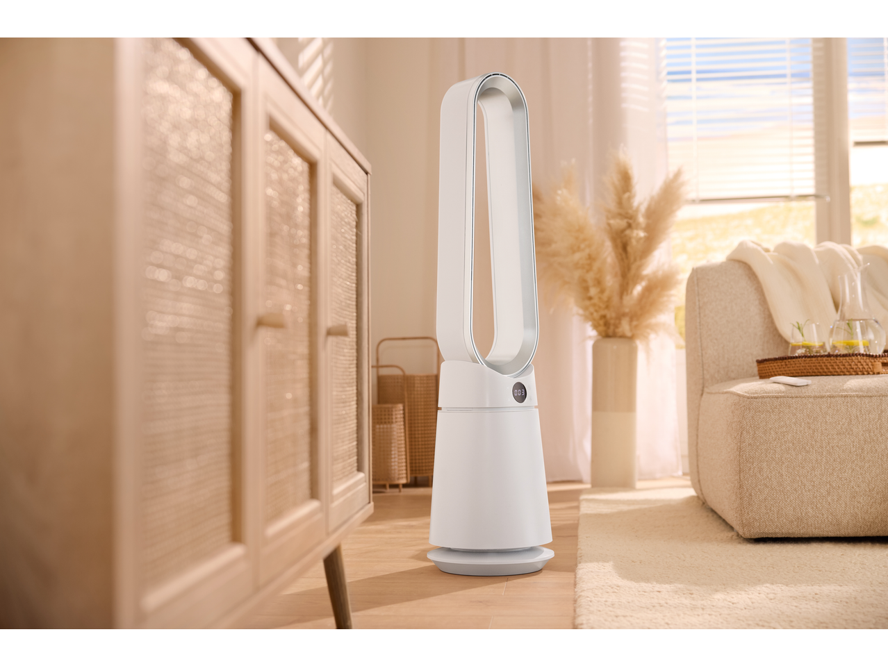 A white air purifier in a living room with a wooden cabinet and a beige sofa.