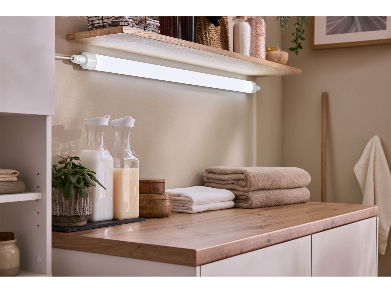 Under-cabinet LED light bar illuminating a countertop with towels and bottles.