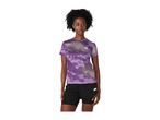 Woman in a purple patterned short-sleeved top and black shorts.