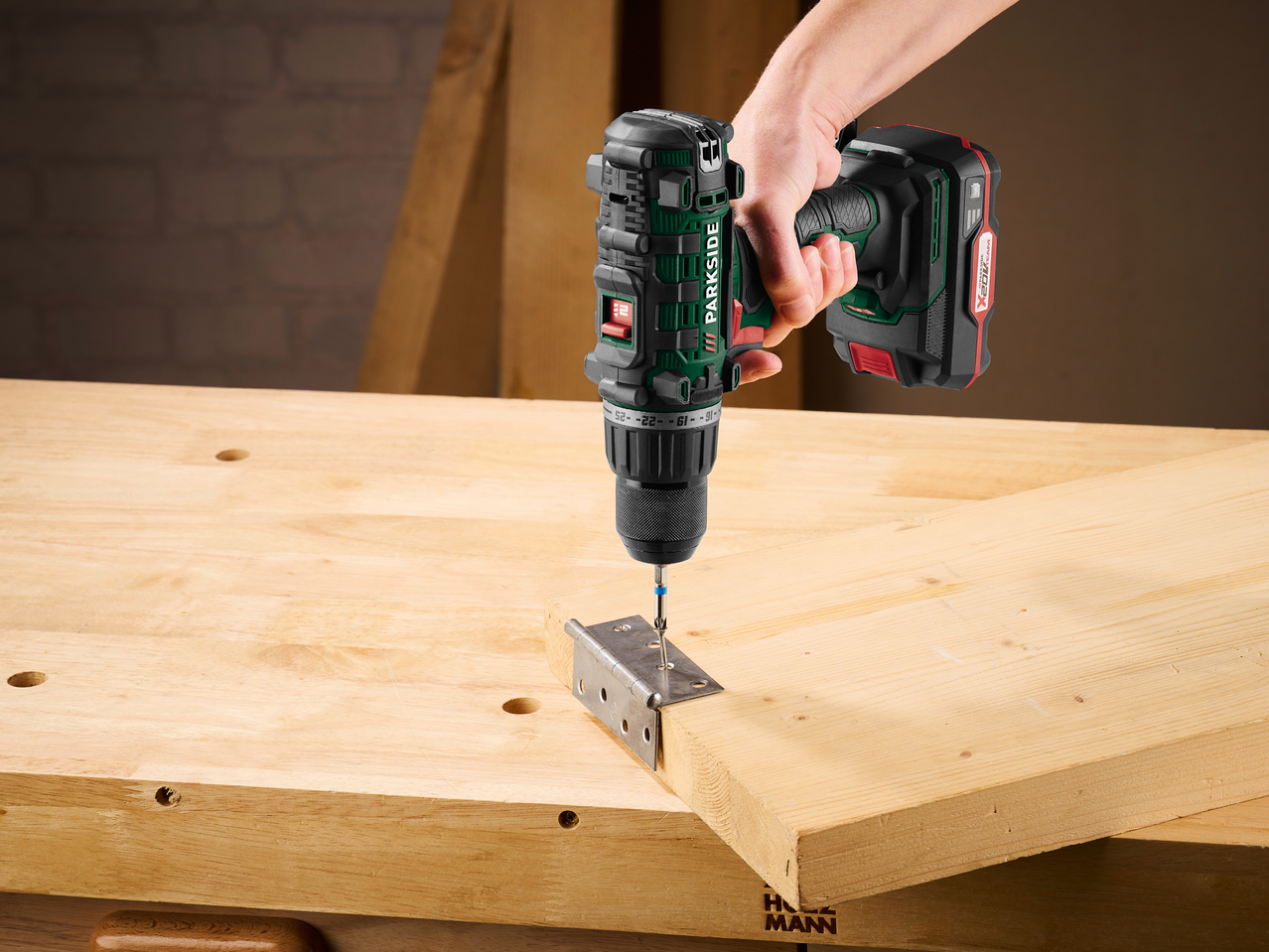 Акумулаторна бормашина завинтва винт в панта, прикрепена към дървена дъска.