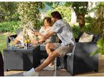 Couple relaxing on a dark grey rattan garden furniture set with drinks and lemons.