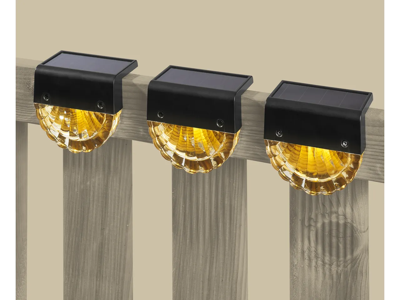 Three Livarno LED solar lights with amber glow mounted on a wooden fence.