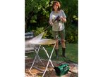 Woman pressure washing a dirty garden table with a compact pressure washer.