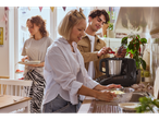 Amigos a cozinhar juntos na cozinha com um processador de alimentos e massa.