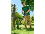 Bărbat folosind un trimmer de gazon PARKSIDE pentru a tăia iarba lângă un gard.