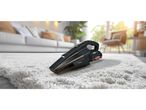 A black handheld vacuum cleaner sits on a fluffy white rug in a living room.