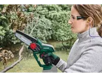 Woman cutting a branch with a cordless wood cutter, wearing safety glasses and earplugs.