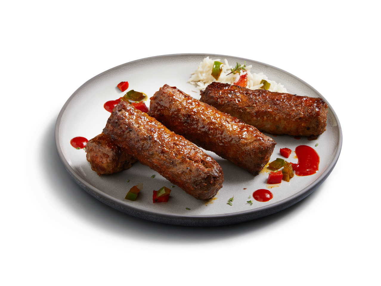 Cevapcici mit Reis und Paprika auf einem Teller.
