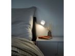 A cozy bedroom scene with a bed, nightstand, and a wall-mounted reading light.