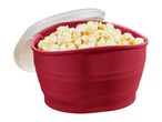 A red silicone popcorn maker filled with popped popcorn, with its lid open.