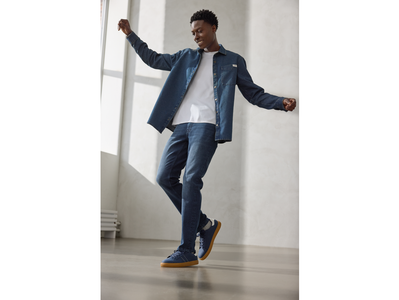 Man wearing an esmara® Men's Denim Shirt, white t-shirt, and jeans, smiling and posing.