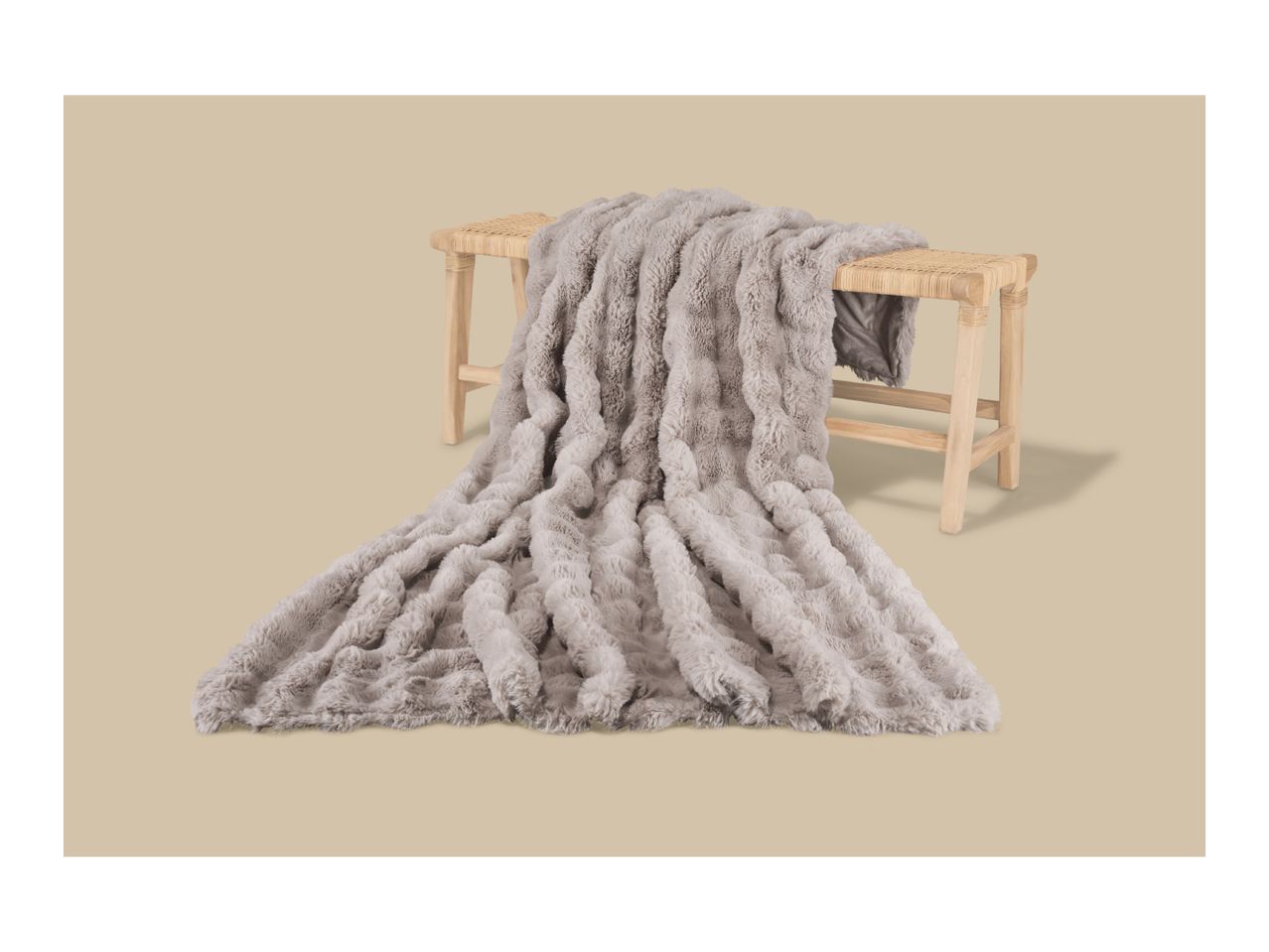 Fluffy grey faux fur blanket draped over a light wooden bench