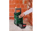 Person inserting a battery into a green portable radio on a construction site.
