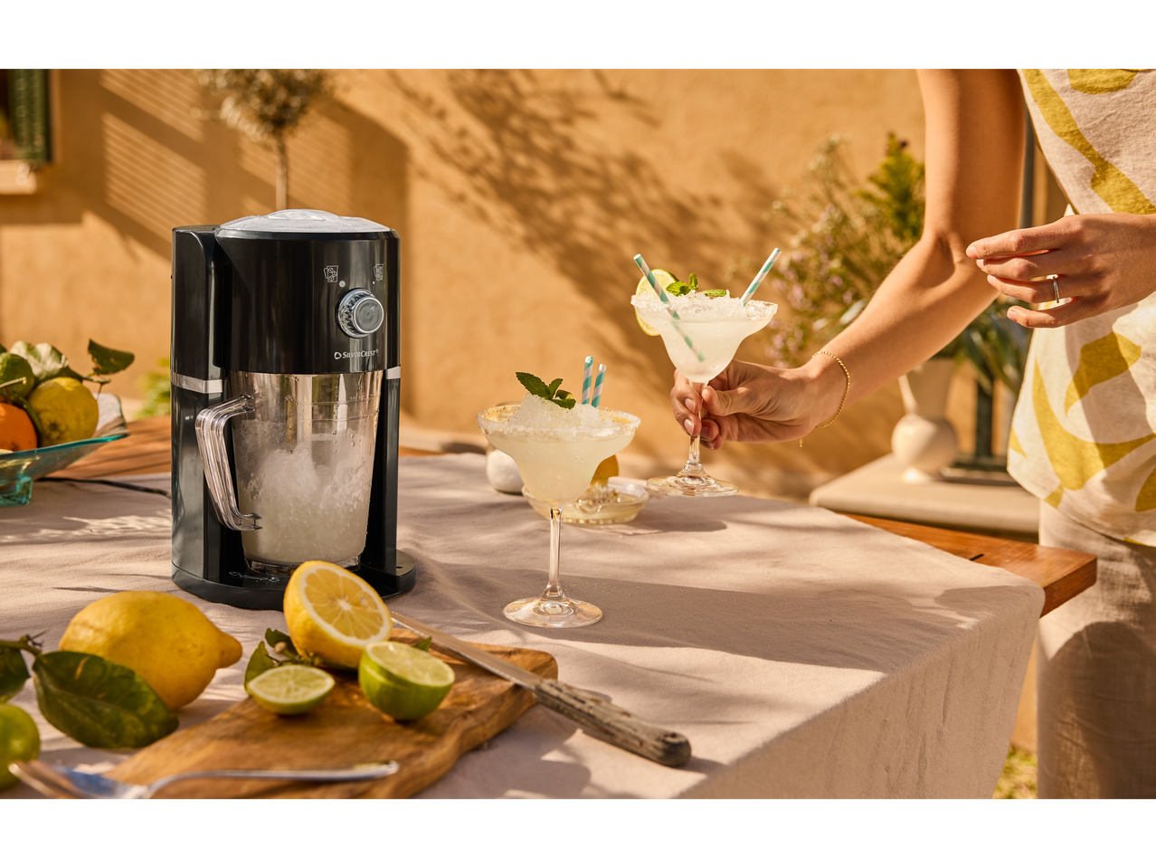 Uma mulher serve margaritas congeladas ao lado de uma máquina de gelo SilverCrest.