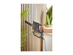 Handheld vacuum cleaner cleaning a slatted wooden wall next to a plant.