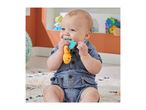 A baby in denim overalls sits on a rug, chewing on a colorful teether toy.