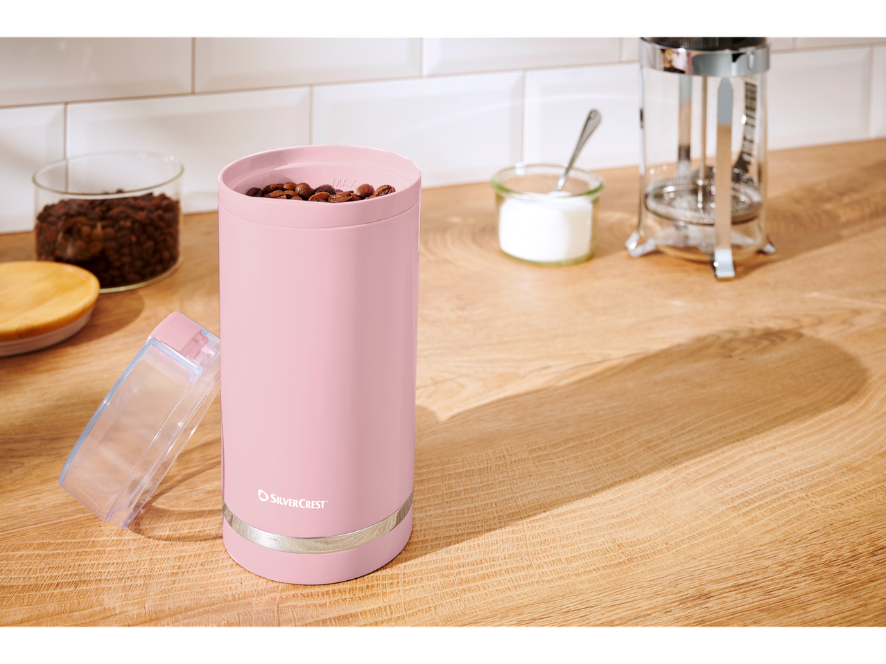 Moedor de café rosa SilverCrest com grãos de café em uma bancada de cozinha