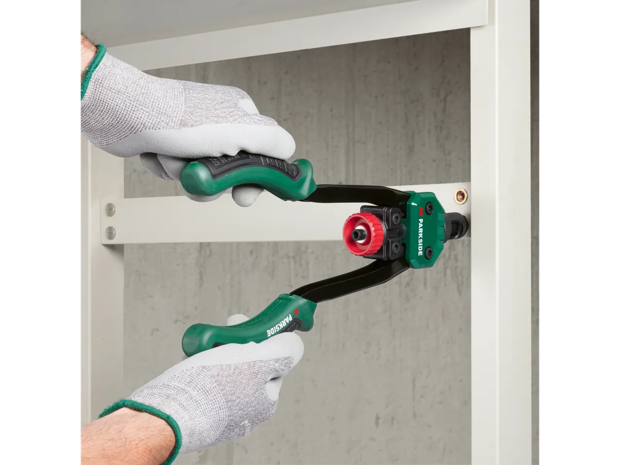 Gloved hand using a Parkside riveting tool on a metal piece.