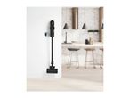Cordless stick vacuum cleaner mounted on a white wall in a modern kitchen.