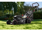 PARKSIDE PERFORMANCE® Petrol Lawnmower on a green lawn with garden foliage in the background.
