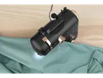 Une machine à coudre Easixx noire utilisée sur un tissu vert clair.