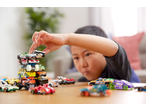 Child stacking Hot Wheels toy cars, with more cars scattered on a wooden table.