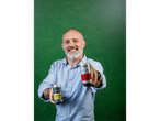 A man holding two Steeper Culture cans, including 'The Haymaker' Ginger & Lemon Kombucha.