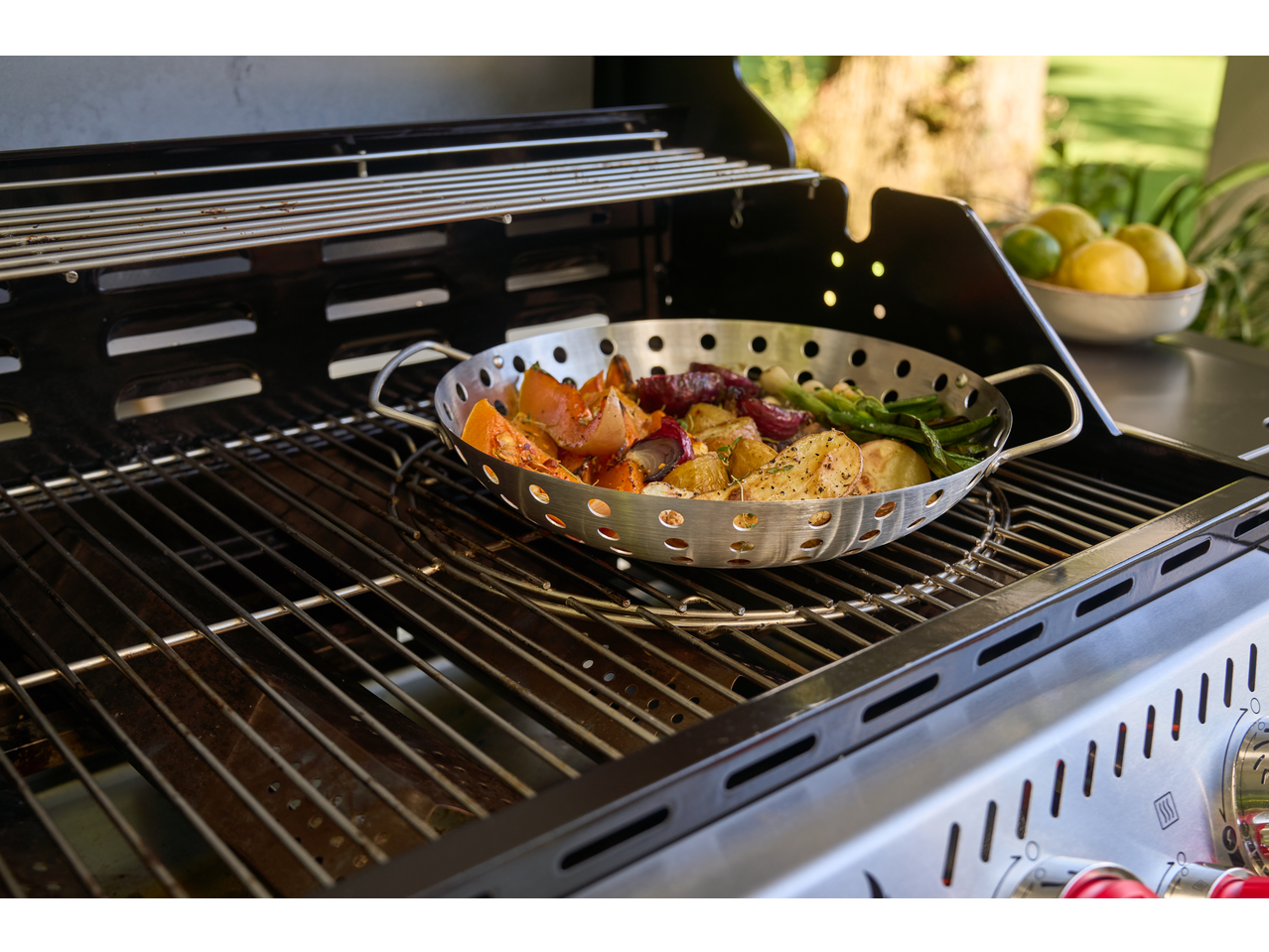 Placă/tigaie Grillmeister cu legume mixte pe un grătar cu gaz.