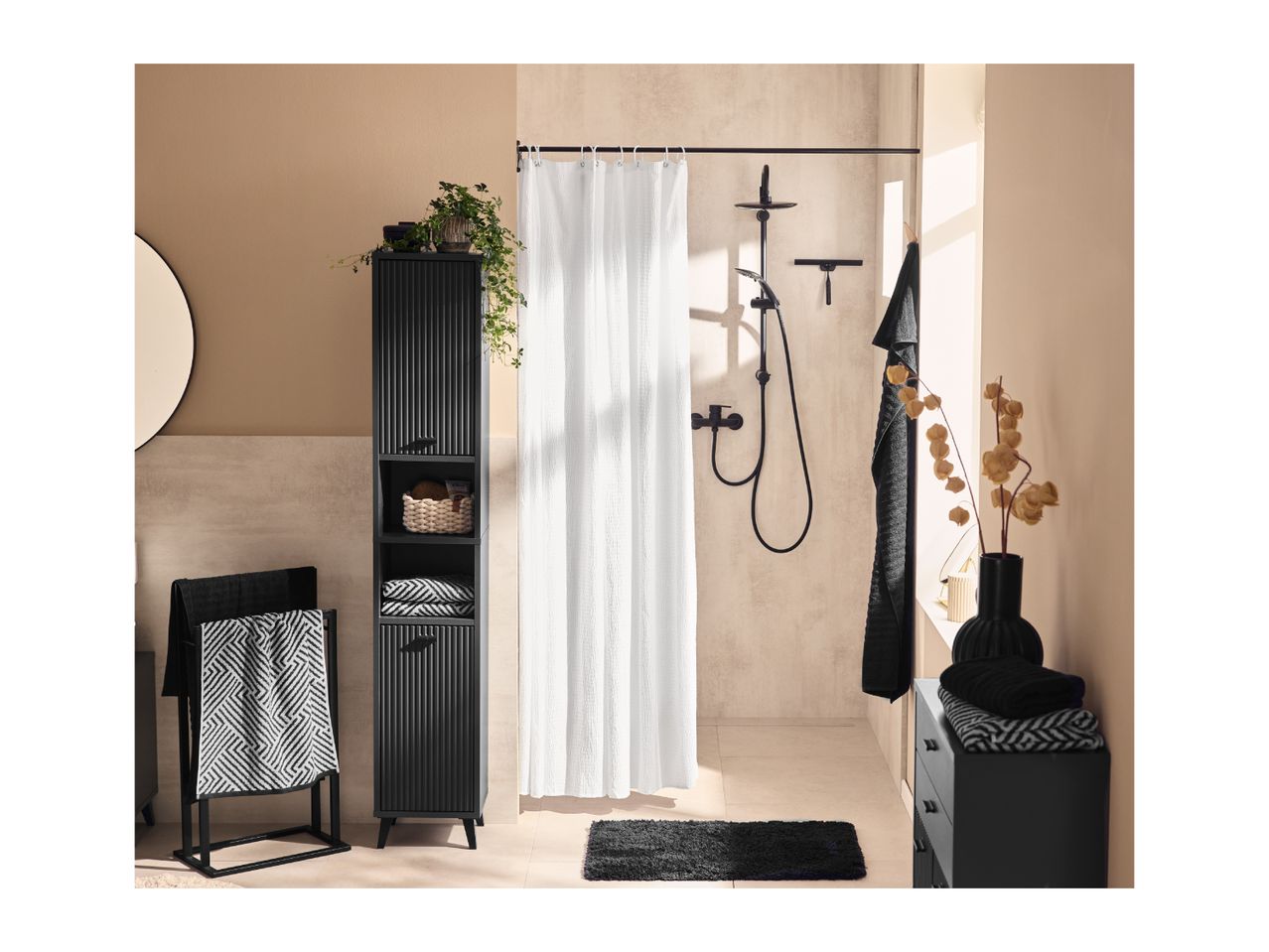 Modern bathroom with black storage cabinet, shower, and towels in black and white patterns.