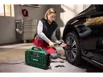 Woman using a Parkside® Portable Compressor to inflate a car tire in a garage.