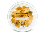 Mosterdkaasblokjes in een glazen schaal.
