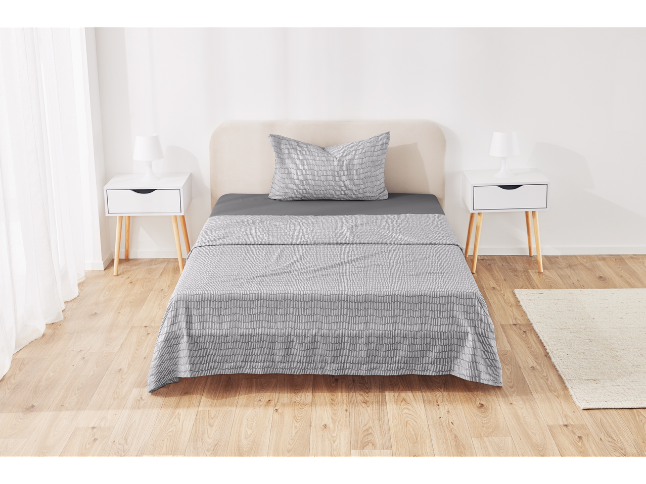 Bedroom with light wood flooring, white nightstands, and gray patterned bedding.
