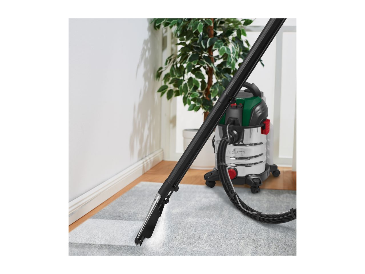 A wet and dry vacuum cleaner being used to clean a grey carpet.