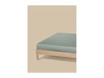 Light green fitted sheet on a wooden bed frame against a beige background.