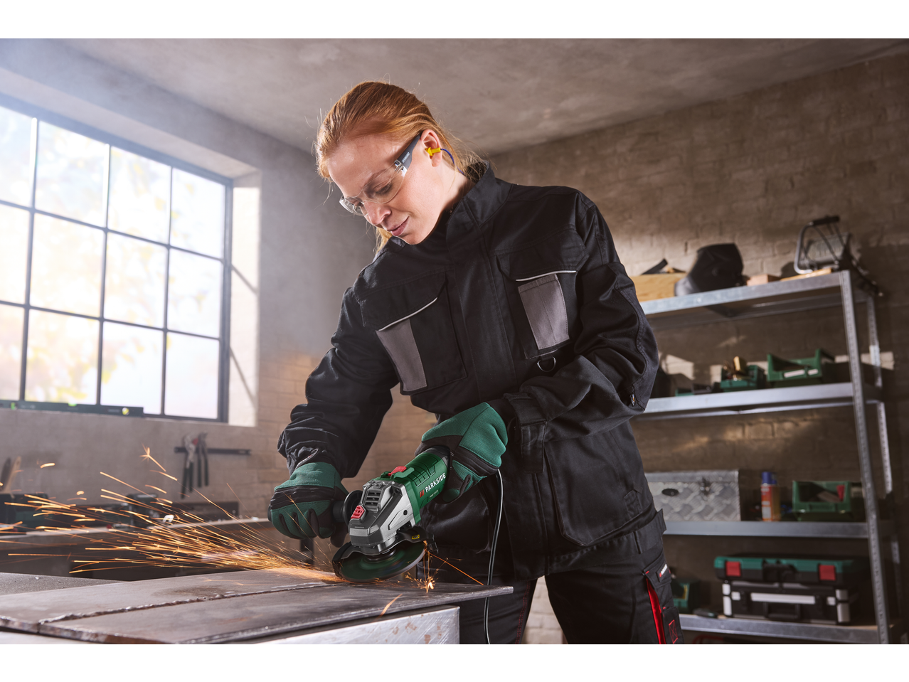 Woman using a PARKSIDE® angle grinder, creating sparks while working on metal.