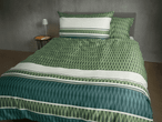 Bettwäsche-Set mit geometrischem Muster in Grün- und Weißtönen auf einem Bett.