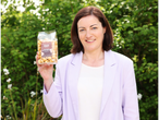 A woman holding a bag of Second Street Bakeshop Gourmet Toffee Popcorn.